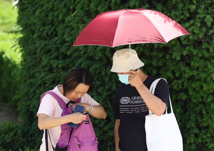 Dos turistas con un paraguas para refugiarse del calor, a 19 de mayo de 2022, en Madrid (España). La Dirección General de Protección Civil y Emergencias ha alertado por un riesgo de altas temperaturas, que pueden alcanzar hasta 40C  en la mitad sur de 