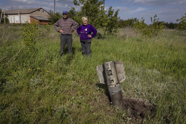 20 de mayo de 2022, Ucrania, Donetsk: Una pareja observa un misil ruso sin explotar que cayó en su jardín, en el límite de la región separatista de Donbás. Foto: Alex Chan Tsz Yuk/SOPA Images vía ZUMA Press Wire/dpa
