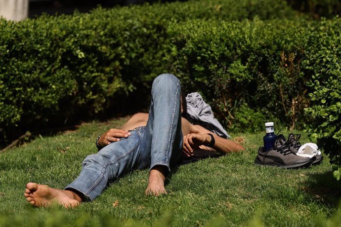 Un hombre tumbado en el césped, a 19 de mayo de 2022, en Madrid (España). 