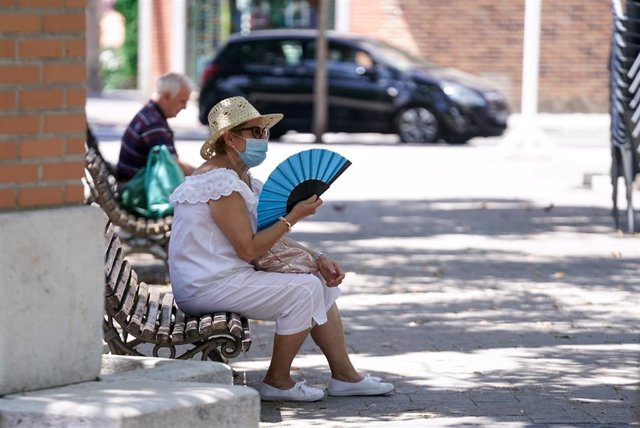 Archivo - Una anciana con mascarilla se abanica sentada en un banco, a 27 de julio de 2021, en Madrid, (España). 