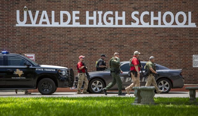 Law enforcement officials inspect the scene near the Uvalde High School. Fourteen students and one teacher were killed in a shooting in an elementary school in the small town of Uvalde Governor Greg Abbott has said in a press conference.