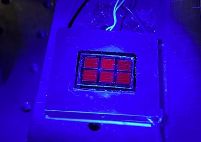La célula solar que establece récords brilla en rojo bajo una luminiscencia azul.
