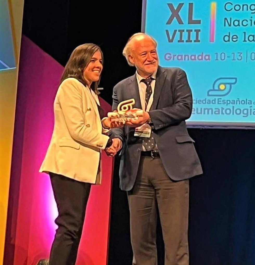 Laura Bautista recoge el premio de manos del presidente de la Sociedad Española de Reumatología, José María Álvaro Gracia.