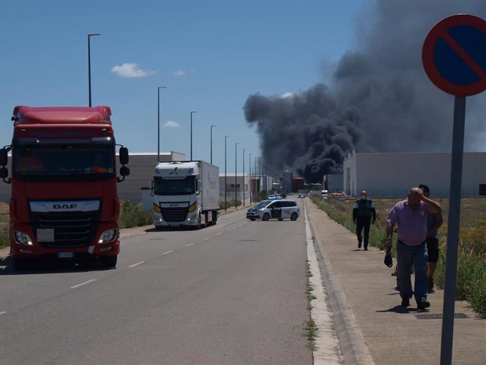 Dos camiones y varias personas delante de una nube negra de humo generada por la explosión en una planta biodiesel de Calahorra, a 26 de mayo de 2022, en Calahorra, La Rioja (España). 
