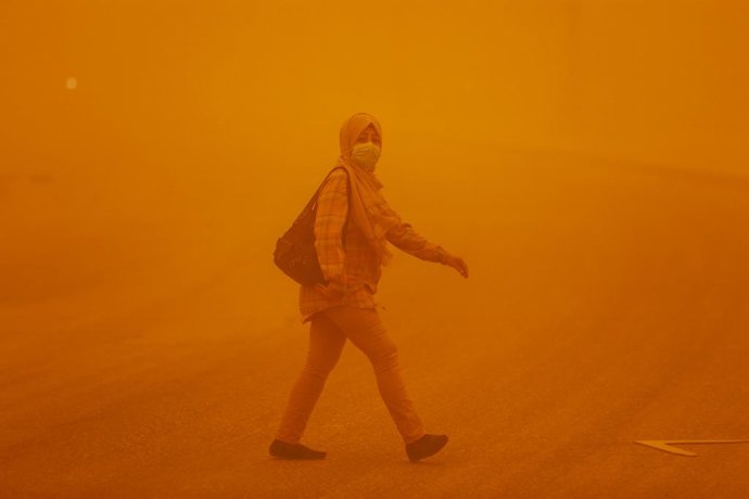 16 May 2022, Iraq, Baghdad: A woman walks on a street covered with yellow dust as a dust storm hit several areas across Iraq sending dozens to hospitals with respiratory problems. Photo: Ameer Al-Mohammedawi/dpa