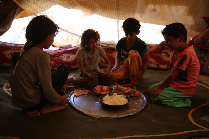 Archivo - 04 July 2021, Syria, Darat Izza: Children eat in a tent inside a camp for displaced persons in Darat Izza, northwest of Aleppo. Aid organisations have warned that an enormous humanitarian crisis would face those displaced but also the rest of 