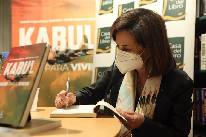 La ministra de Defensa, Margarita Robles, firma en el acto de presentación del libro Kabul. Huir para vivir