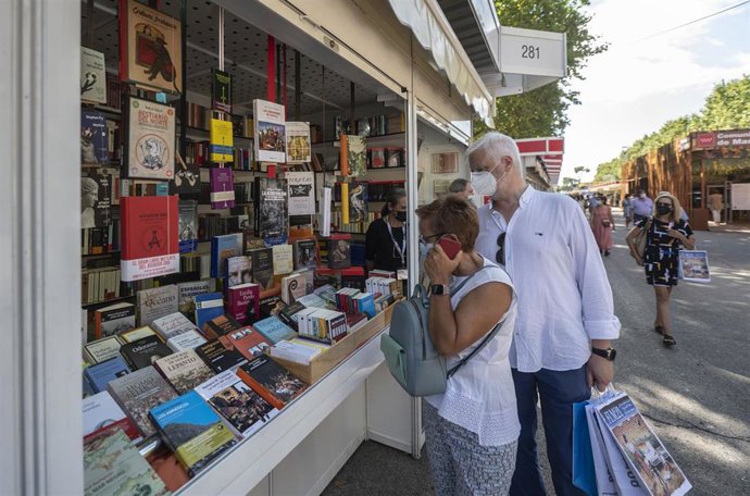Archivo - Clientes y paseantes visitan la Feria del Libro de Madrid