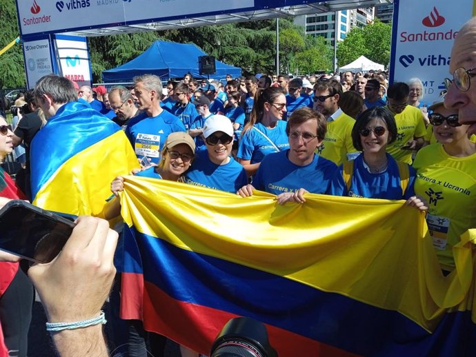 El alcalde de Madrid, José Luis Martínez-Almeida, posando con la bandera de Ucrania junto a corredores.