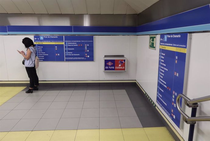 Archivo - Una mujer consulta el móvil en la estación de Metro de Sol.