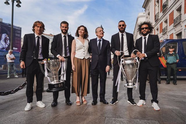 La presidenta de la Comunidad de Madrid, Isabel Díaz Ayuso, junto al presidente del Real Madrid y varios de sus jugadores posando conla decimocuarta Copa de Europa lograda en París por el club blanco