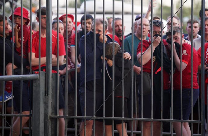 Un grupo de aficionados del Liverpool a las puertas del Stade de France esperando para entrear mientras algunos de ellos se tapan la cara por los gases lacrimógenos lanzados por la Policía.