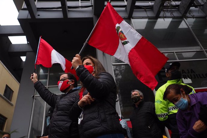 Dos personas onden sendas banderas de Perú.