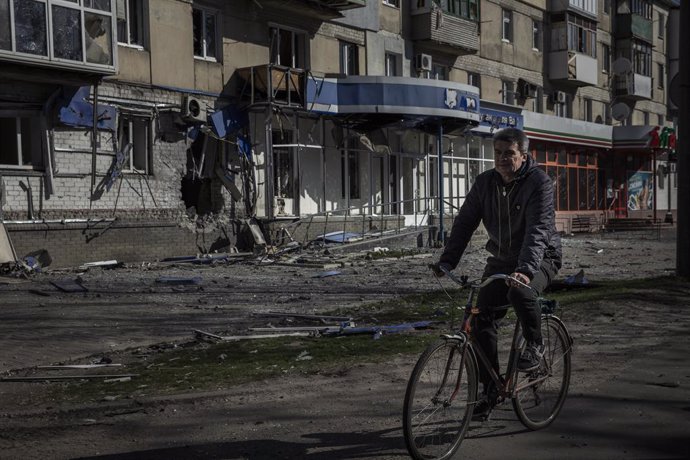 Archivo - Un hombre en bicicleta cerca de un edificio dañado por los ataques del Ejército de Rusia contra la ciudad de Severodonetsk, en el este de Ucrania
