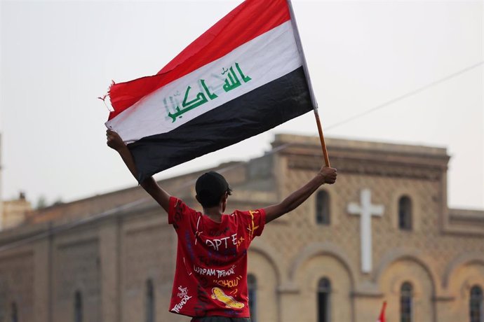 Archivo - Un manifestante sostiene una bandera en la plaza Tahrir de la capital iraquí de Baghdad.