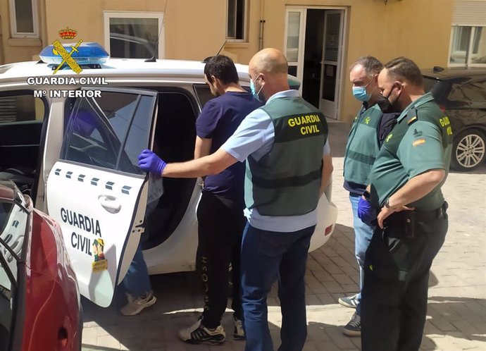 Uno de los detenidos entra en un coche de la Guardia Civil tras ser arrestado