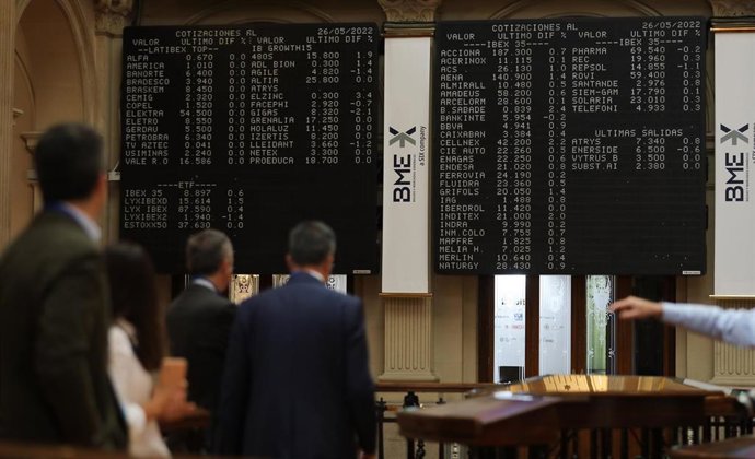 Varias personas frente a los paneles de valores del IBEX 35 en el Palacio de la Bolsa de Madrid, a 26 de mayo de 2022, en Madrid (España).