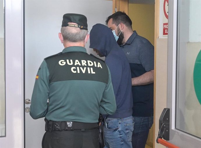 Dos agentes llevan al hombre detenido por haber agredido supuestamente a su pareja, para ser puesto en disposición judicial, en el Juzgado de Instrucción número 1, a 1 de junio de 2022, en Carballo, A Coruña, Galicia (España). El acusado propinó, presun