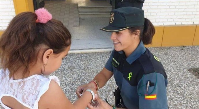 Una guardia civil coloca una pulsera identificativa a una menor en El Rocío.