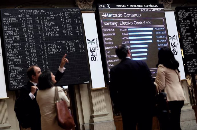 Cuatro personas frente a un panel de valores del Ibex 25 en el Palacio de la Bolsa, a 30 de mayo de 2022, en Madrid (España). El Ibex 35 ha retrocedido un 0,14 % en la media sesión de este lunes, hasta situarse en los 8.920, 9 puntos en una jornada marc