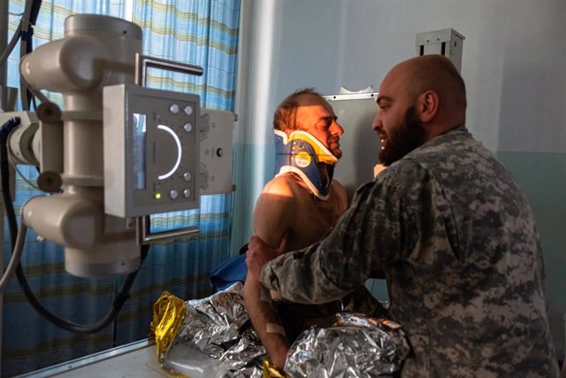 15 May 2022, Ukraine, Pokrovskoe: A doctor from the Georgian legion examines a soldier who suffered a concussion and spinal trauma at Pokrovskoe hospital. The hospital is small but very important to stabilise the conditions of soldiers injured on the fron