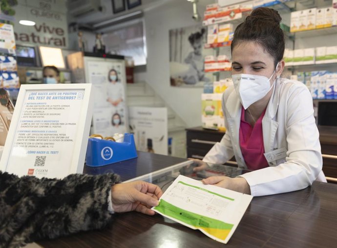 Archivo - Una farmacéutica muestra un test de antígenos a una persona en la farmacia Las Gemelas, a 10 de enero de 2022, en Madrid (España). El presidente del Gobierno, ha anunciado que el Gobierno tiene previsto controlar los precios de los test de a