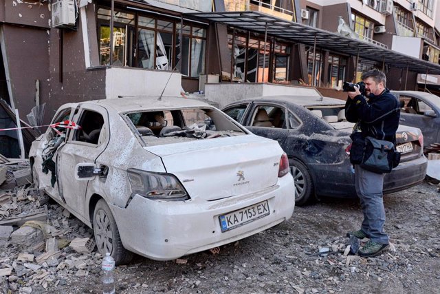 Archivo - Un periodista toma una foto de un coche destruido en Ucrania durante la guerra