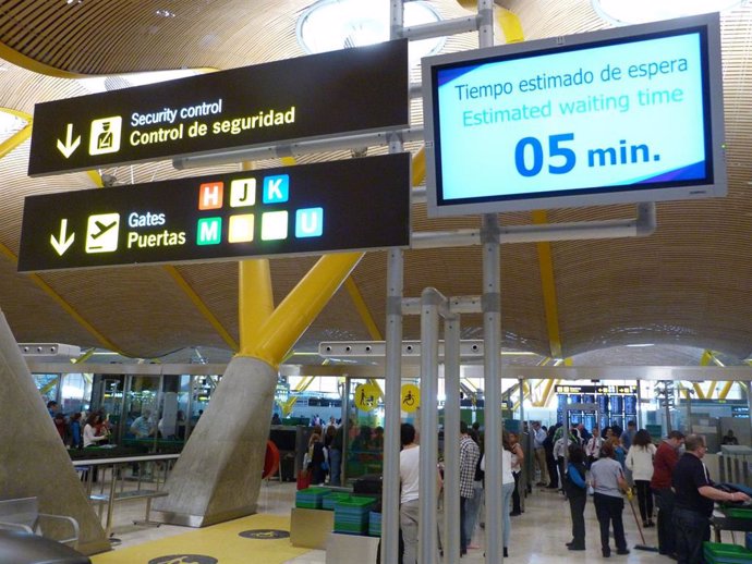 Archivo - Pantallas de información sobre el tiempo de espera en el control de seguridad del Aeropuerto de Barajas