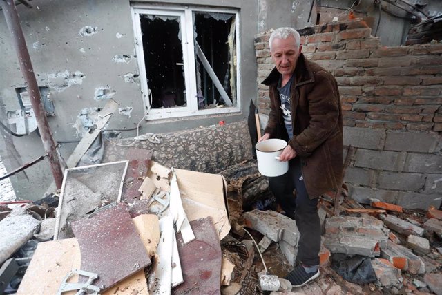 Archivo - Un hombre frente a una casa dañada por los combates en Donetsk, en el este de Ucrania