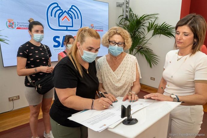 Una de las beneficiarias firma el documento de entrega