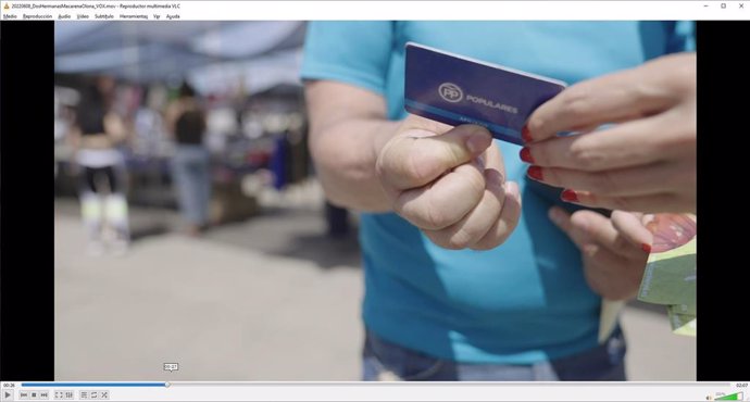 Captura de pantalla en el momento en que un militante del PP enseña su carnet a la candidata de Vox, Macarena Olona, antes de romperlo en Dos Hermanas (Sevilla).