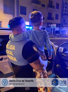 Un agente de la Policía Local de Santa Cruz de Tenerife sostiene en brazos al niño que fue encontrado deambulando solo y en pijama por la calle San Sebastián