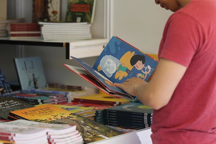 Una persona hojea un libro infantil durante el inicio de la Feria del Libro 2022.