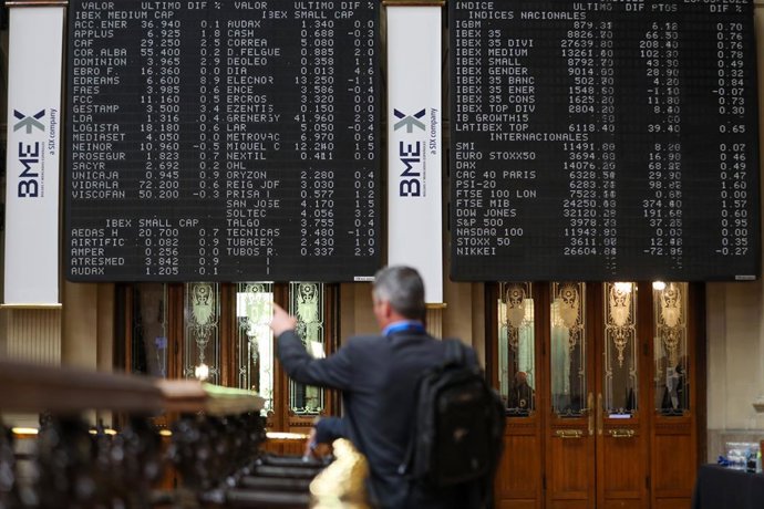 Un hombre señala los paneles de valores del IBEX 35 en el Palacio de la Bolsa de Madrid, a 26 de mayo de 2022, en Madrid (España). 