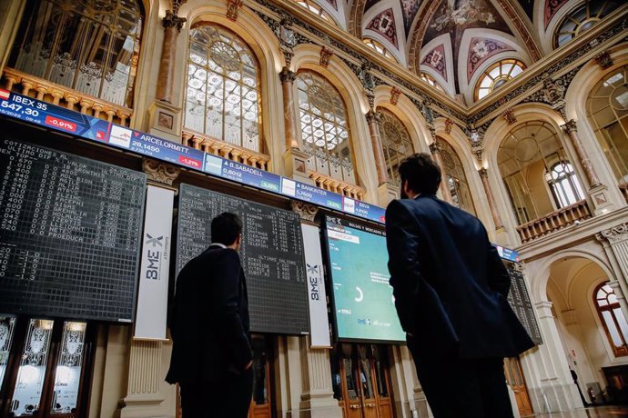 Dos personas observan los paneles del interior del Palacio de la Bolsa de Madrid, a 24 de mayo de 2022, en Madrid (España).