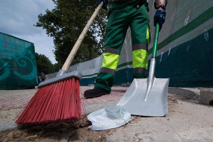 Archivo - Un trabajador de la limpieza recoge una mascarilla tendida en el suelo. En Madrid, (España), a 26 de mayo de 2020.