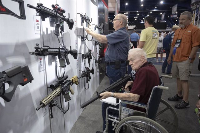Un anciano en silla de ruedas frente a unos fusiles en una exposición de la Asociación Nacional del Rifle (NRA) en Houston, Texas, Estados Unidos