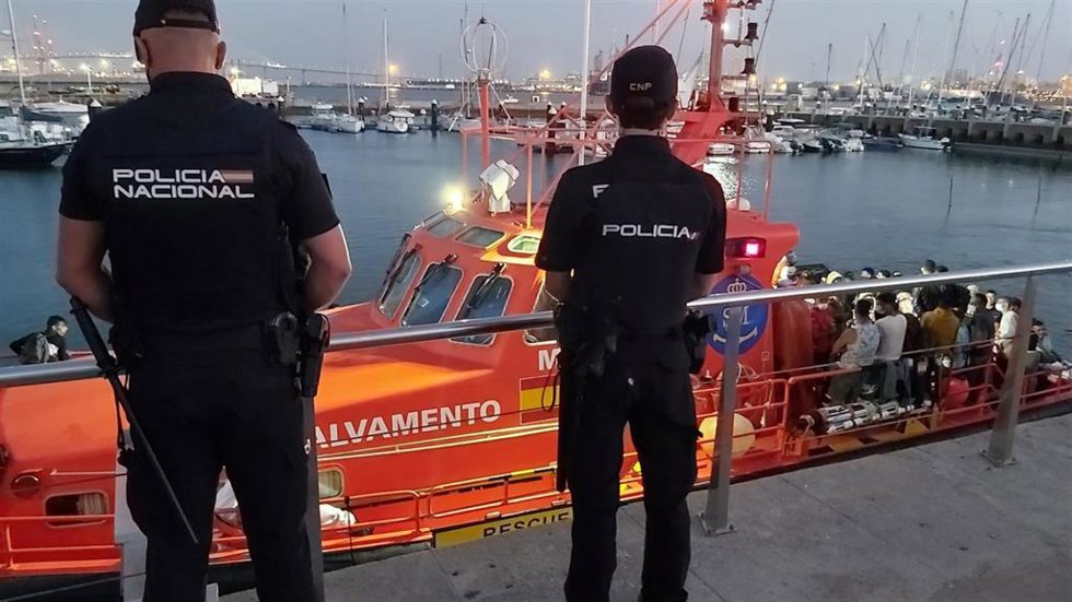 Archivo - Agentes de la Policía Nacional junto a una embarcación de Salvamento que rescató a migrantes de una patera en 2021