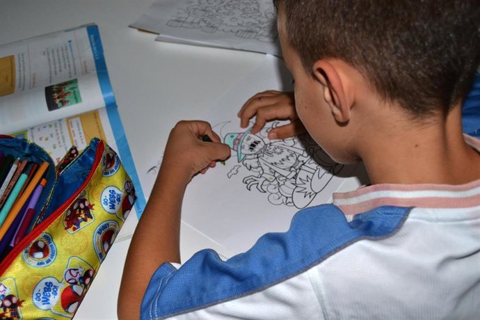 Archivo - Un menor dibuja en una de las viviendas aportadas por Cáritas Diocesana para familias con necesidades