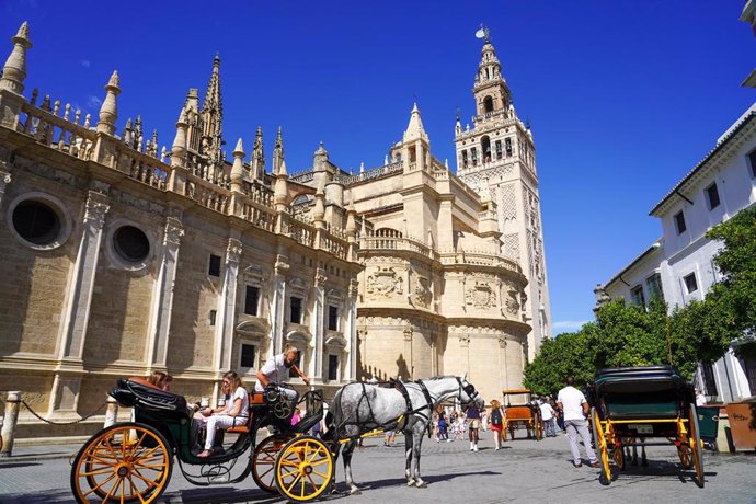 Archivo - Turistas por el entorno de  la Catedral de Sevilla, en foto de archivo.