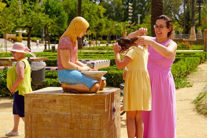 Una madre refresca a su hija en una fuente de el Parque de Maria Luisa  en la primera ola de calor con temperaturas que sobrepasaran los 40 grados a 12 de junio del 2022 en Sevilla (Andalucía, España)