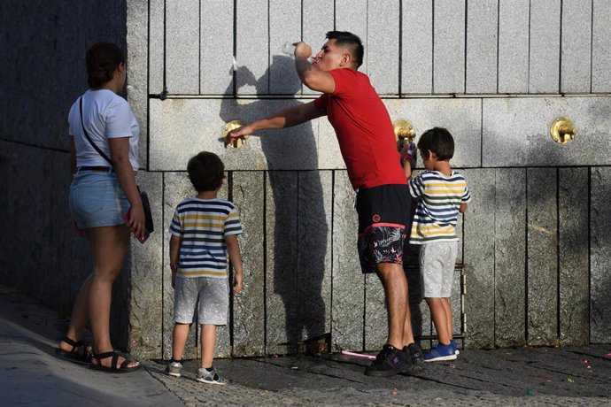 Un grupo de personas bebe en una fuente, en Madrid Río 