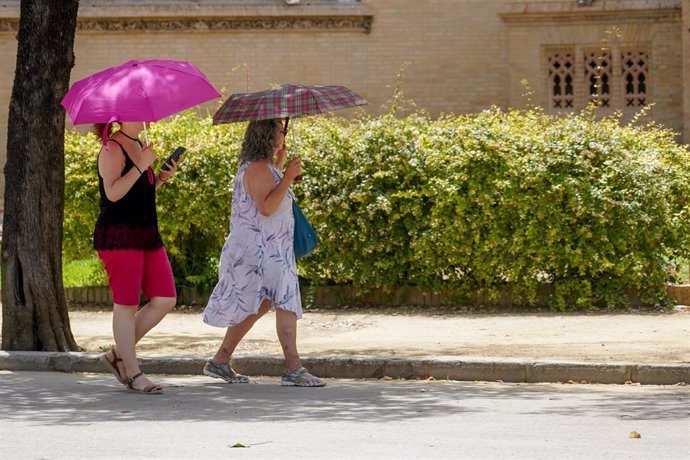 Dos mujeres con un paraguas pasean por el Parque de Maria Luisa en la primera ola de calor con temperaturas que sobrepasaran los 40 grados a 12 de junio del 2022 en Sevilla (Andalucía, España)
