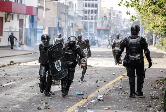 07 October 2019, Ecuador, Quito: Security forces run across a road covered with stones and broken glass during protests against the increase in fuel prices. Photo: Juan Diego Montenegro/dpa