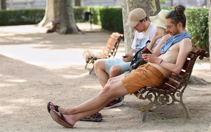 Tres personas descansan en un banco en una jornada de sol y calor