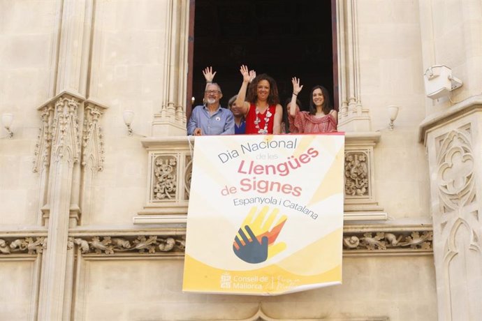 La presidenta del Consell de Mallorca, Catalina Cladera, cuelga un cartel en el balcón de la institución insular con motivo del Día Nacional de la Lengua de Signos.