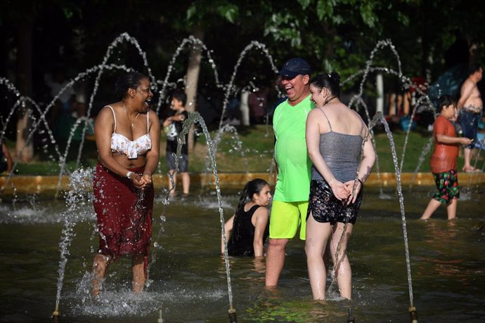 Un grupo de personas disfruta en la fuente transitable conocida popularmente como los chorros o la playa de Madrid Río