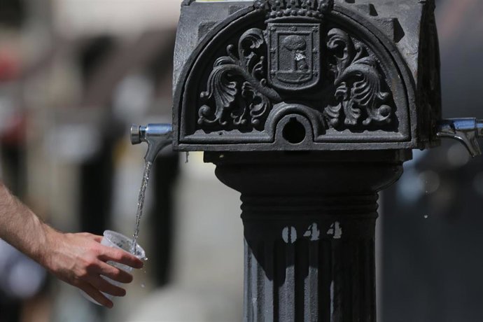 Una persona coge agua de una fuente el día en que España ha comenzado a sufrir un "importante" episodio cálido 