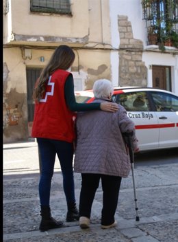 Una voluntaria de Cruz Roja acompaña a una mujer mayor.