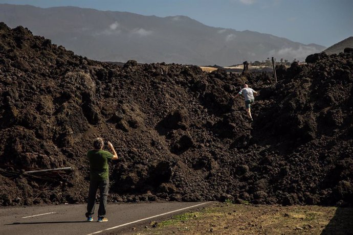 Archivo - Un turista se sube a la colada mientras otro le hace una foto, a 12 de febrero de 2022, en Tazacorte, La Palma, Santa Cruz de Tenerife, Canarias (España). Las diferentes coladas del volcán Cumbre Vieja, cubrieron más de 1300 hectáreas en 85 dí